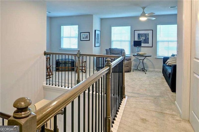 hall with carpet floors, baseboards, plenty of natural light, and an upstairs landing