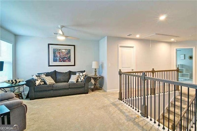 living room featuring light carpet, ceiling fan, attic access, and baseboards