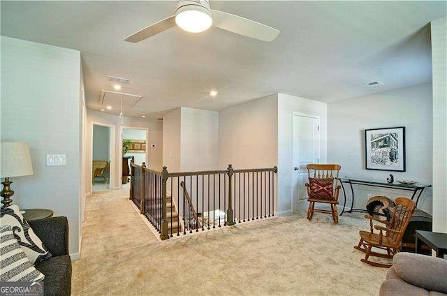 sitting room featuring visible vents, an upstairs landing, a ceiling fan, carpet, and attic access