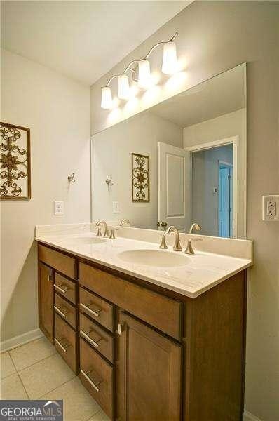 full bath with double vanity, baseboards, a sink, and tile patterned floors