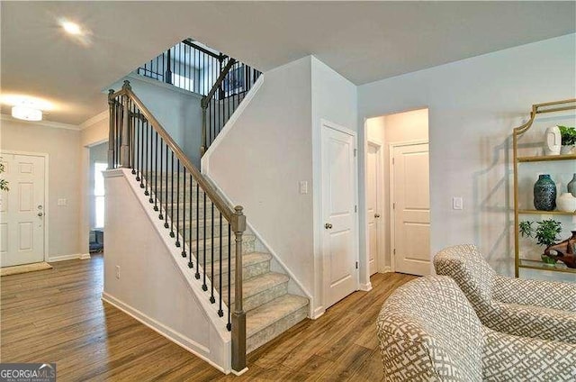 stairway featuring crown molding, wood finished floors, and baseboards