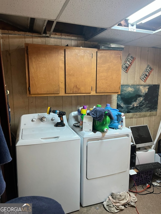 laundry room featuring cabinet space, wood walls, and separate washer and dryer