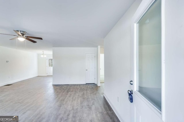 unfurnished living room with visible vents, wood finished floors, a ceiling fan, and baseboards