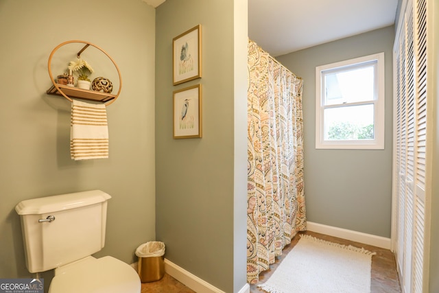 bathroom with toilet, baseboards, and a shower with shower curtain