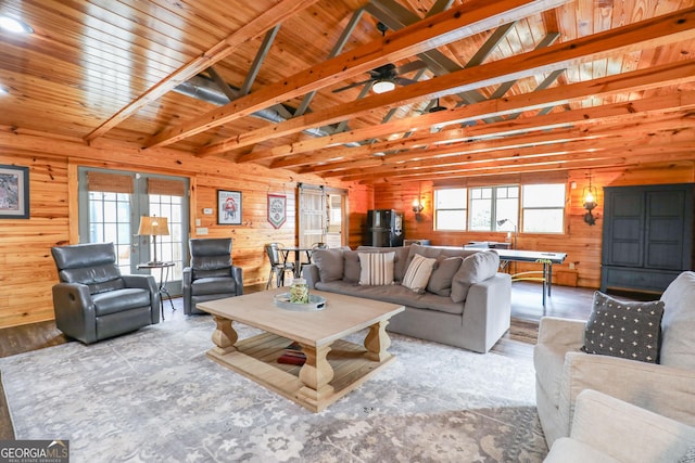 living area with vaulted ceiling with beams, a healthy amount of sunlight, wood walls, and wood finished floors