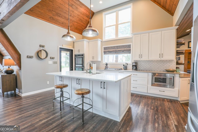 kitchen with an island with sink, wooden ceiling, appliances with stainless steel finishes, light countertops, and high vaulted ceiling
