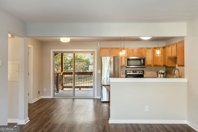 kitchen with dark wood-style flooring, baseboards, appliances with stainless steel finishes, decorative backsplash, and pendant lighting