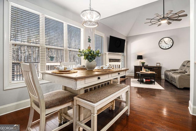 dining space with a fireplace, baseboards, vaulted ceiling, and hardwood / wood-style floors