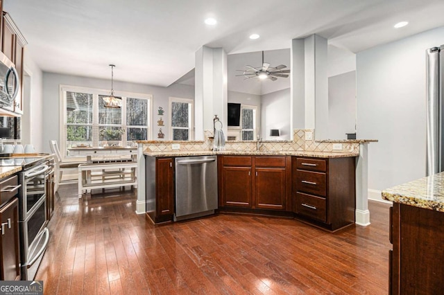 kitchen featuring light stone counters, dark wood finished floors, recessed lighting, appliances with stainless steel finishes, and ceiling fan with notable chandelier