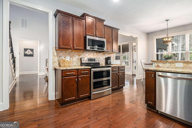 kitchen featuring dark wood-style floors, appliances with stainless steel finishes, backsplash, and light stone countertops