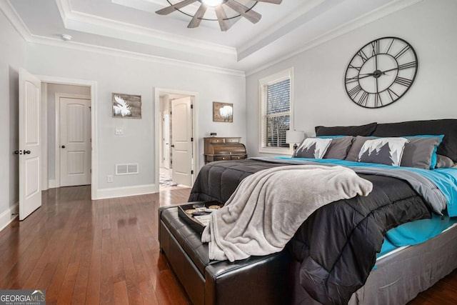 bedroom with visible vents, a raised ceiling, hardwood / wood-style flooring, and baseboards