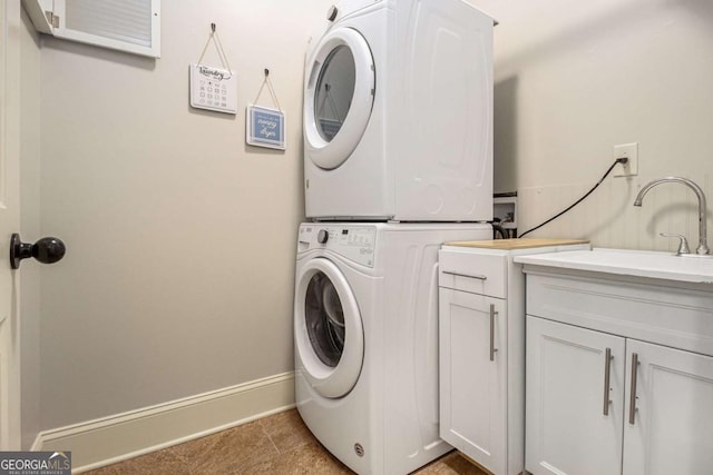 laundry room with cabinet space, light tile patterned flooring, baseboards, and stacked washer and clothes dryer