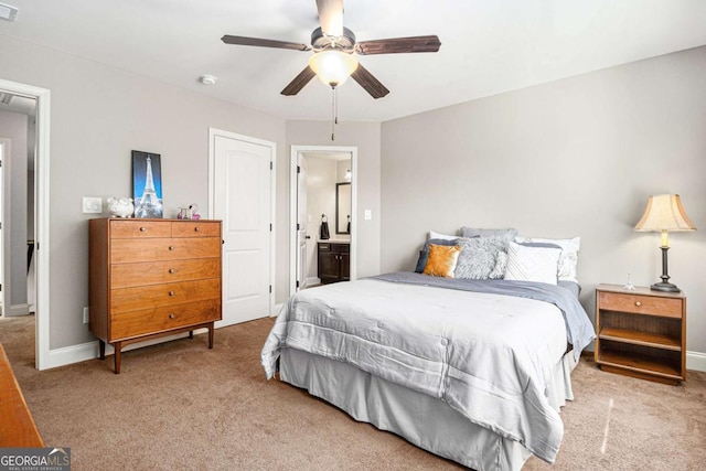 carpeted bedroom with visible vents, ceiling fan, ensuite bath, and baseboards