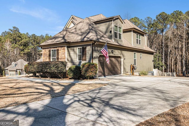 view of home's exterior with a shingled roof and driveway