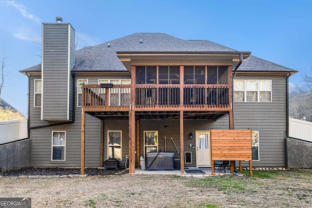 rear view of house featuring fence, a sunroom, a chimney, a patio area, and a hot tub