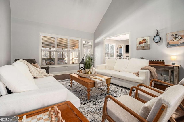 living area featuring high vaulted ceiling, baseboards, and wood finished floors