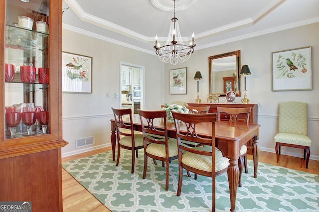 dining space with baseboards, light wood-style flooring, visible vents, and a notable chandelier