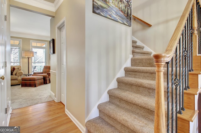 stairway with crown molding, baseboards, and wood finished floors