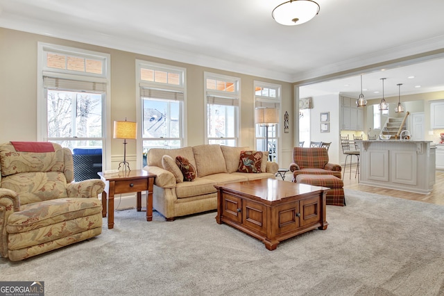 living area featuring light carpet, stairs, and crown molding