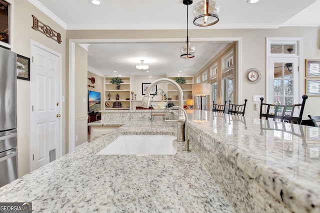 kitchen with light stone counters, built in features, crown molding, freestanding refrigerator, and a sink