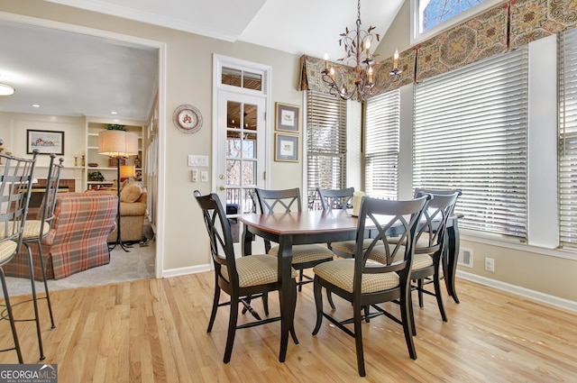 dining area with a notable chandelier, light wood finished floors, visible vents, vaulted ceiling, and baseboards