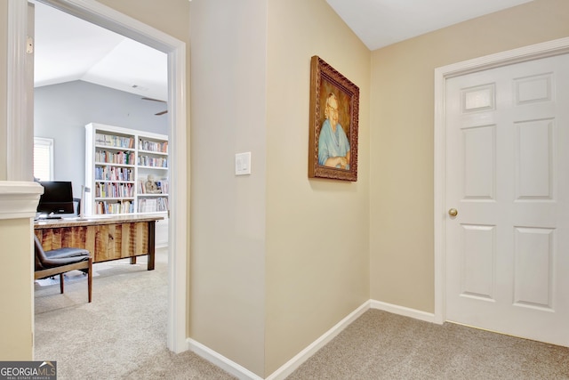 corridor featuring lofted ceiling, carpet, and baseboards