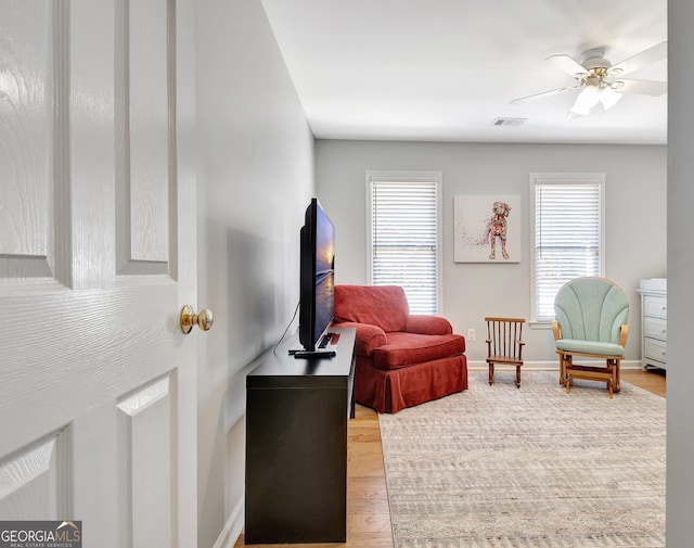 living area featuring plenty of natural light, visible vents, ceiling fan, and wood finished floors