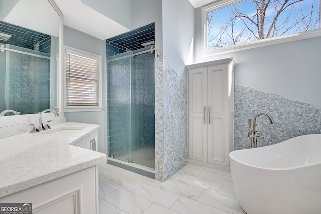 full bathroom with a stall shower, a soaking tub, marble finish floor, vanity, and tile walls