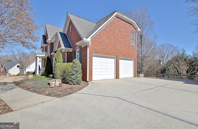 view of side of property with a garage, driveway, brick siding, and a shingled roof