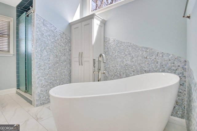 bathroom featuring marble finish floor, a shower stall, and tile walls