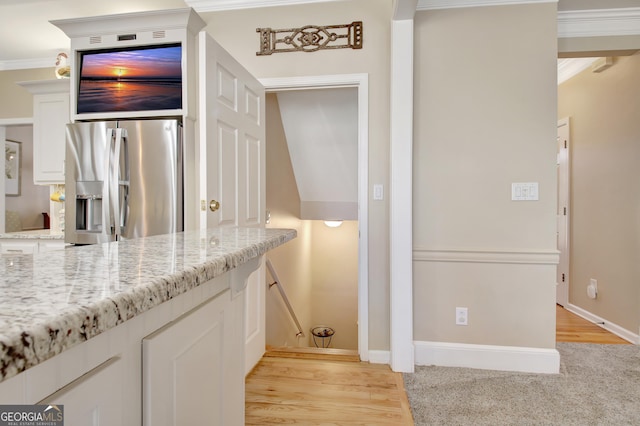 kitchen featuring white cabinets, light stone countertops, stainless steel refrigerator with ice dispenser, and crown molding