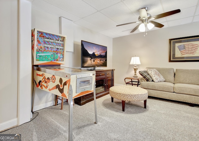 carpeted living room featuring baseboards, a drop ceiling, and a ceiling fan