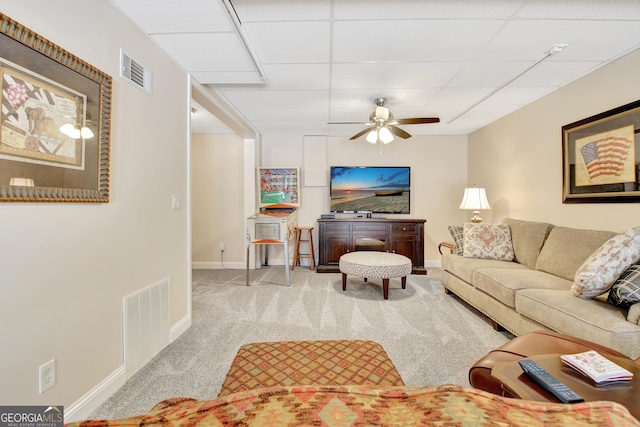 carpeted living area featuring ceiling fan, a drop ceiling, visible vents, and baseboards