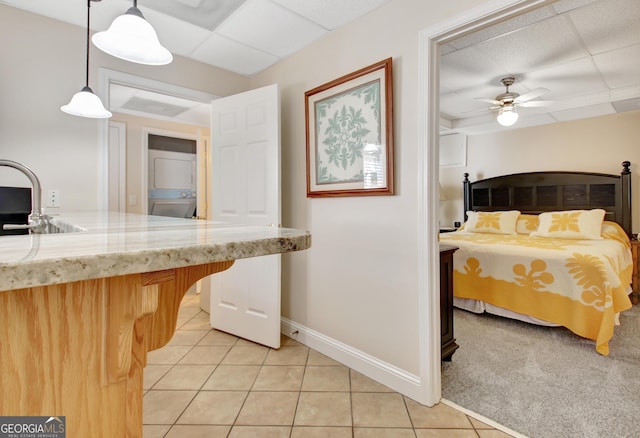 kitchen featuring ceiling fan, a sink, hanging light fixtures, and light tile patterned floors