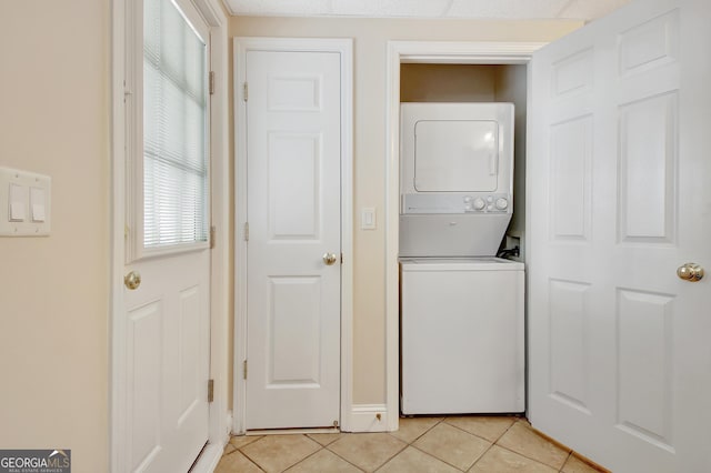 laundry room featuring laundry area, stacked washer and clothes dryer, and light tile patterned floors