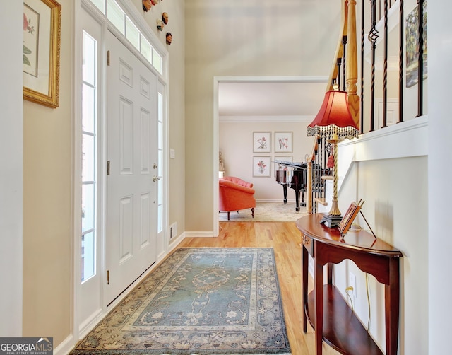 entryway with baseboards, visible vents, ornamental molding, and wood finished floors