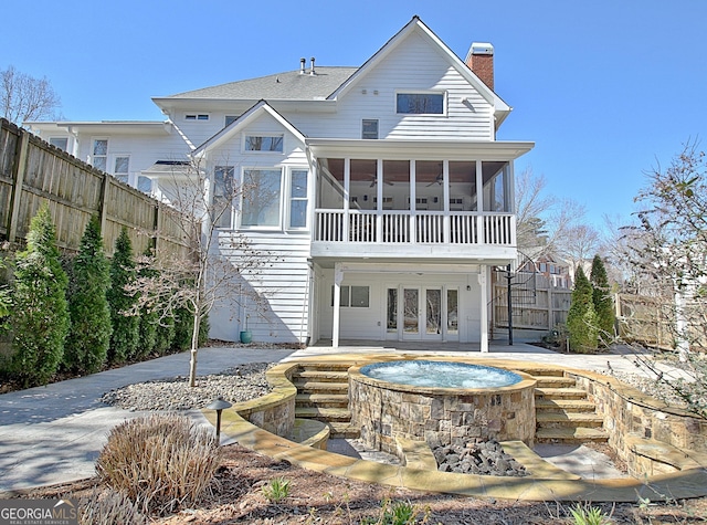 back of property with french doors, a patio, a chimney, a sunroom, and fence