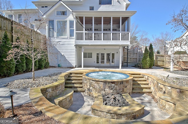 rear view of property with an outdoor hot tub, a patio area, a fenced backyard, and a sunroom