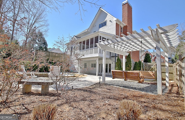 back of house featuring a sunroom, a fenced backyard, a pergola, and a patio