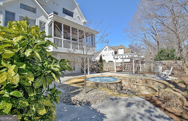 exterior space with a sunroom, an outdoor hot tub, fence, and a patio