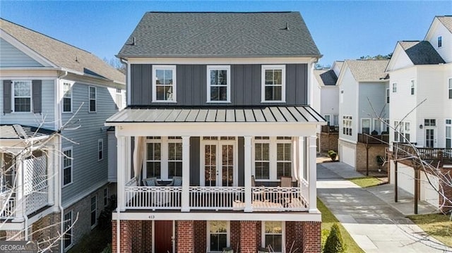 view of front of house featuring a standing seam roof, french doors, board and batten siding, and brick siding