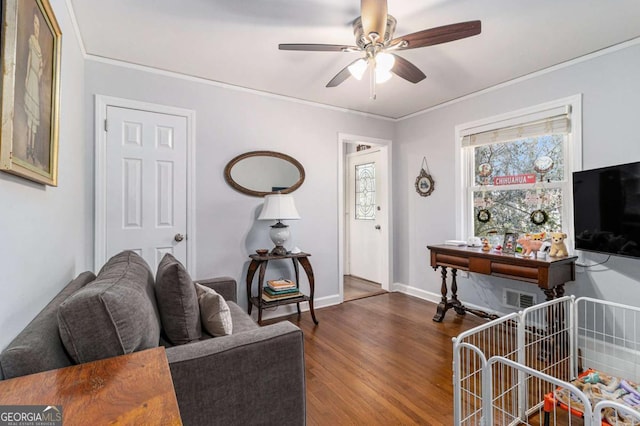 living area featuring ceiling fan, dark wood-type flooring, visible vents, baseboards, and crown molding