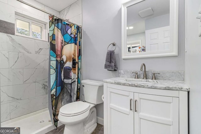bathroom featuring toilet, a tile shower, and vanity