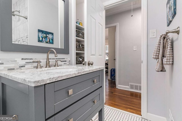 bathroom featuring baseboards, visible vents, wood finished floors, and vanity