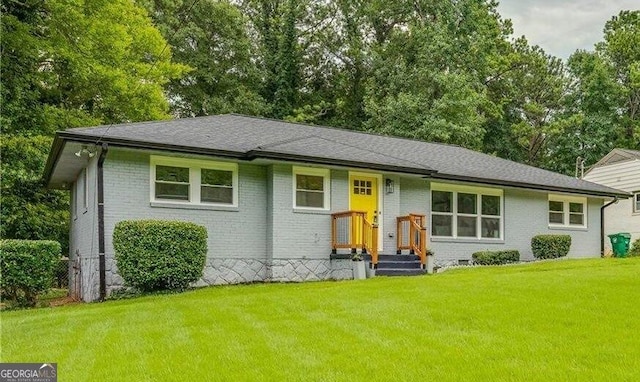 ranch-style house featuring a shingled roof, a front lawn, and brick siding