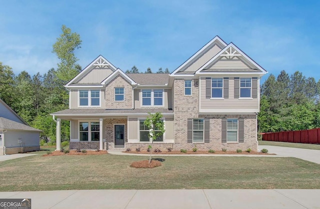 craftsman house featuring a front yard, fence, and brick siding