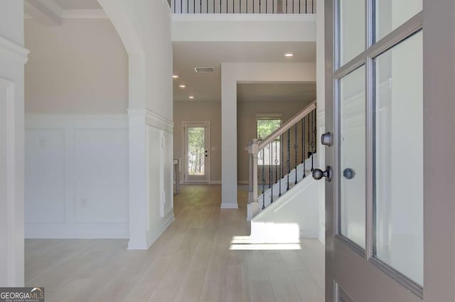 entryway with visible vents, wainscoting, stairway, wood finished floors, and a decorative wall