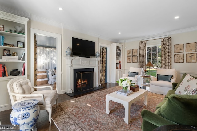 living room with a warm lit fireplace, recessed lighting, crown molding, and wood finished floors