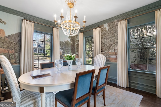 dining room featuring crown molding, wallpapered walls, wood finished floors, and an inviting chandelier