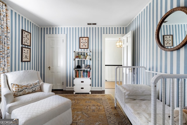 living area with baseboards, wood finished floors, visible vents, and wallpapered walls